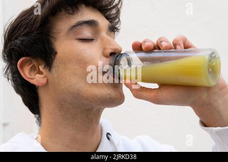Carefree male drinking natural orange juice from bottle while enjoying taste with closed eyes Stock Photo