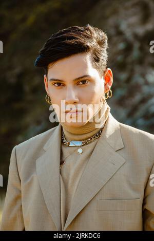Young ethnic male model in stylish suit looking at camera on sunny day in countryside Stock Photo