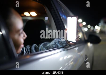 Side view of smiling female passenger on backseat browsing mobile phone with blank screen in city at night Stock Photo