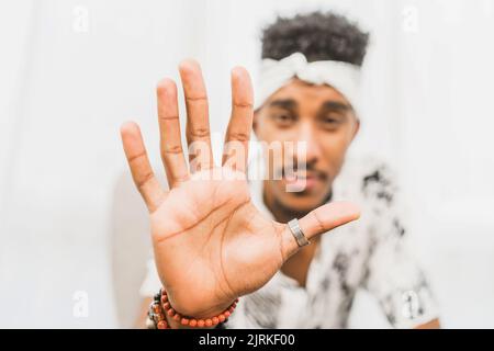Blurred ethnic male showing stop sign while looking at camera on white background Stock Photo