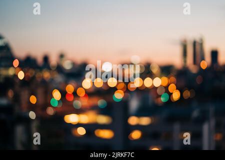 Bright glowing lights of district in megapolis under dusk sky in evening on blurred background Stock Photo