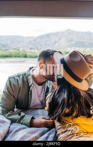 Couple kissing while relaxing in camper van Stock Photo - Alamy