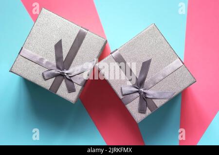 Two silver gift boxes on a blue and pink background. Flat lay Stock Photo