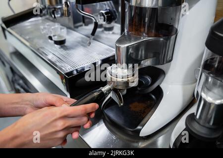 From above of crop unrecognizable barista with portafilter preparing aromatic drink in coffee machine in cafe Stock Photo