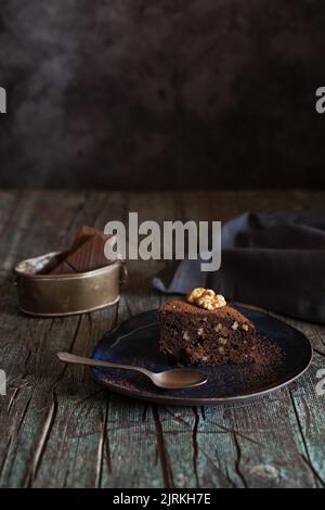 Detail of Piece of brownie cake with walnuts on a dish on wood background Stock Photo