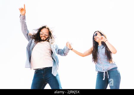 Smiling bearded Latin American man pointing up while holding content girlfriend by hand and having fun on sunny day Stock Photo