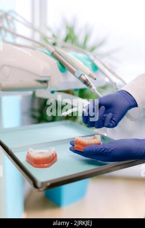 From above of crop unrecognizable orthodontist in sterile gloves with jaw casts and transparent braces in clinic Stock Photo
