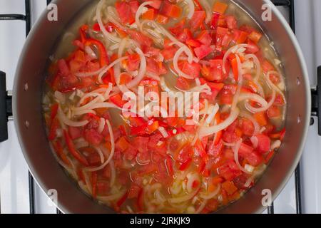 Top view of chopped tomatoes and onions in pot cooking on stove for lunch Stock Photo