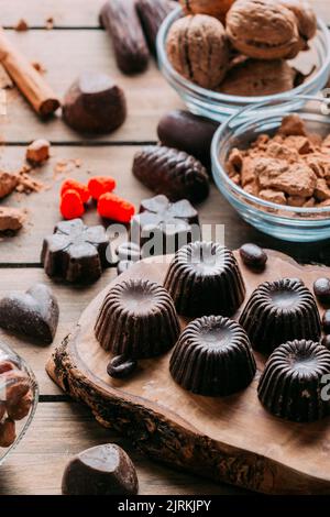 Various handmade chocolates with nuts arranged on wooden table with cinnamon sticks Stock Photo