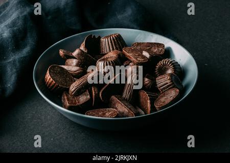 Assorted dark chocolate truffles and pralines in various shapes in bowl placed on black table Stock Photo