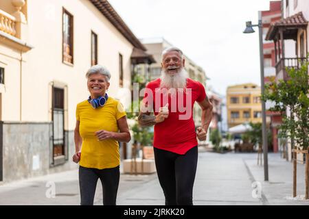 Lower angle of a happy senior couple running in the city Stock Photo