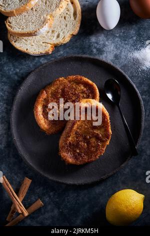 Plate of freshly prepared yummy torrija arranged with eggs and lemon on table in kitchen Stock Photo