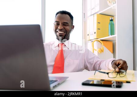 Smiling black male entrepreneur working on netbook in modern office Stock Photo