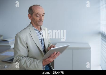 Aged business executive using application on digital tablet Stock Photo
