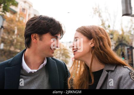 Cheerful young woman having fun with boyfriend during romantic date on city street looking at each other Stock Photo
