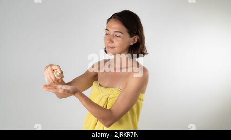 A woman squeezes the cream serum on the palm of her hand after a shower - body and face care at home Stock Photo