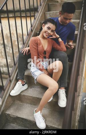 Beautiful young Asian woman resting on stairs with her boyfriend Stock Photo