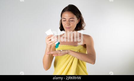 Woman squeezes hand cream out of tube - face and body care at home Stock Photo