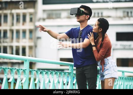 Young woman hedging her boyfriend who is using VR glasses Stock Photo
