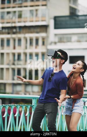Excited young Vietnamese couple using VR goggles Stock Photo