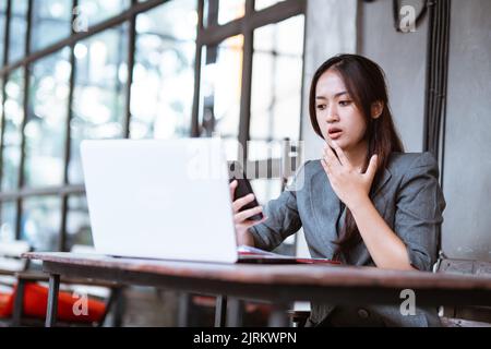 confused young businesswoman while using her mobile phone during working Stock Photo