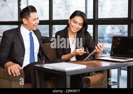 businessman and woman having a relaxed meeting using tablet in cafe Stock Photo