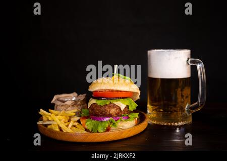 tasty hamburger burger sandwich with french fries and ketchup on a wooden tray a glass of cool beer with foam fast food black background Stock Photo