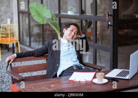 relaxed young businessman sitting in cafe using laptop Stock Photo