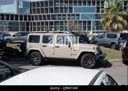 A side view of a sand-colored Jeep Wrangler Limited off-road car parked with other vehicles Stock Photo