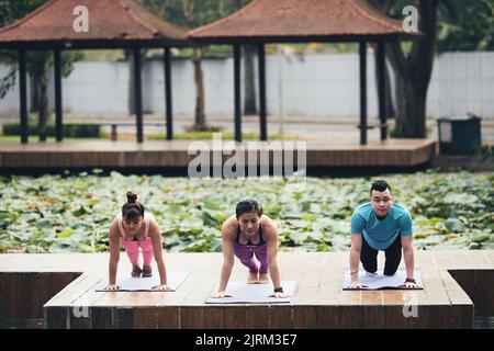 Group of Vietnamese young people doing plank together outdoors Stock Photo