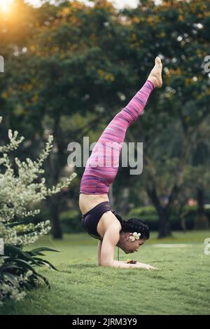 Side view of Asian young woman performing handstand Stock Photo