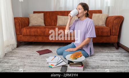 Female student drinks coffee while studying at home Stock Photo