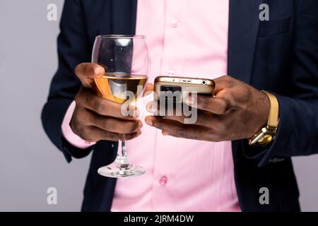 black person holding glass of wine and using phone Stock Photo