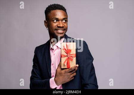 african man wearing a suit posing with a gift Stock Photo