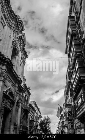 A vertical shot of a cloudy sky and buildings in grayscale Stock Photo