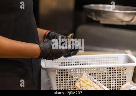 Unrecognizable fishmonger cleaning a mussel in the municipal market of Vigo (Spain). Stock Photo