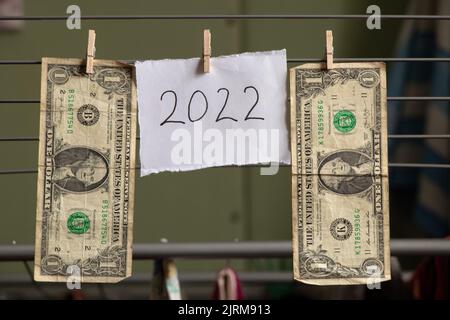 dollars are weighing on a rope on clothespins and next to a card with the text 2022, happy new year, finance in the new year Stock Photo