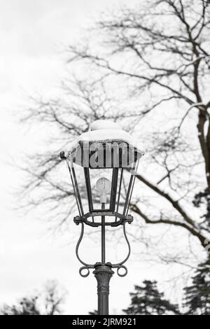 Retro classic snow-covered street light with modern electric balb in calm park Stock Photo