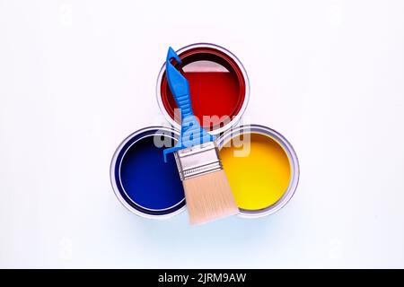 colorful open paint can red blue and yellow brush on it isolated on white background Stock Photo