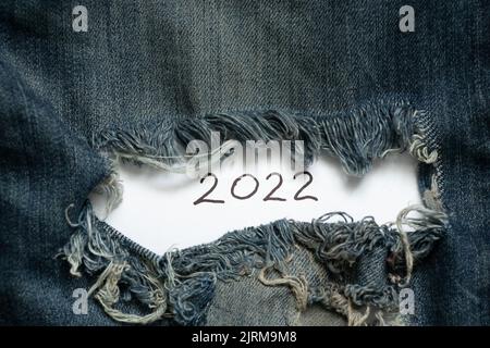 2022 written on paper that lies on torn jeans, happy new year 2022, holiday and fashion