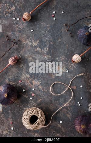 Autumn fruits, black fig and yellow plums on wooden tray. Flat lay, top view on dark textured background with dry poppy plants Stock Photo