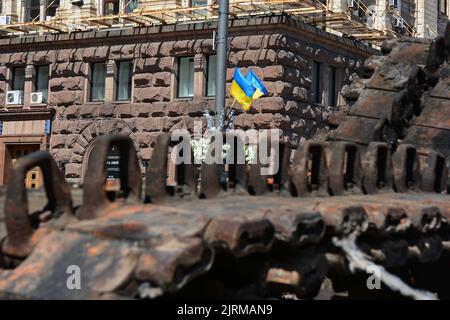 The flag of Ukraine is next to burnt caterpillars from a destroyed Russian army tank displayed at Khreshchatyk in the center of Kyiv. Captured Russian military equipment is being temporarily displayed on Khreschaytk street in the heart of the Ukrainian capital. The area has become a popular attraction among residents curious to see Ukraine's spoils of war. (Photo by Aleksandr Gusev / SOPA Images/Sipa USA) Stock Photo