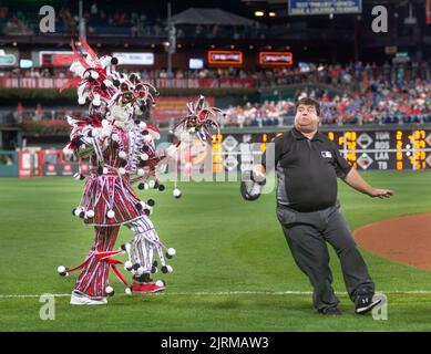 Philadelphia, United States. 24th Aug, 2022. WMMR's Jacky Bam Bam wears his prize winning Mummers costume as he dances on field while teasing faux umpire Chris Morris at third base with the Phillies Phanatic between the 5th and 6th innings of the Cincinnati Reds at Philadelphia Phillies baseball game Wednesday, August 24, 2022 at Citizens Bank Park in Philadelphia, Pennsylvania. The Phillies held Mummers Night in celebration of the group and their New Years Parade tradition. Credit: William Thomas Cain/Alamy Live News Stock Photo