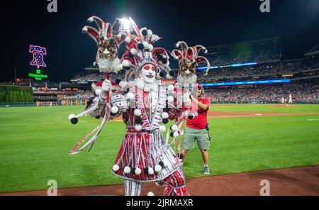 WMMR's Jacky Bam Bam wears his prize winning Mummers costume as he dances on field at third base with the Phillies Phanatic between the 5th and 6th innings of the Cincinnati Reds at Philadelphia Phillies baseball game Wednesday, August 24, 2022 at Citizens Bank Park in Philadelphia, Pennsylvania. The Phillies held Mummers Night in celebration of the group and their New Years Parade tradition. Thirty percent of Phillies ticket sales went to the Mummers clubs, who now fund the annual parade themselves after the city of Philadelphia stopped offering prize money a number of years ago. (Photo b Stock Photo