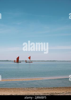 Two historic red sailed Thames Sailing Barges heading out along the Blackwater estuary at Bradwell Waterside, Bradwell On Sea, Essex England UK Stock Photo