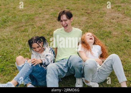 Three young people having fun and laughing in the park while recording trending videos on mobile phone. Youth lifestyle. Having fun. Stock Photo