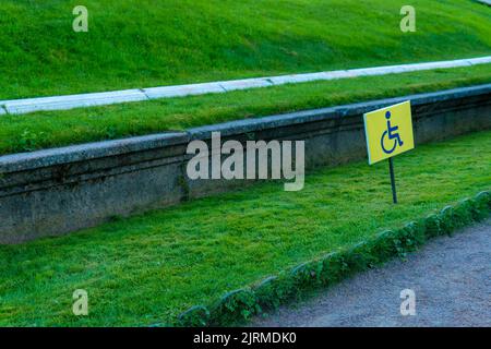 RUSSIA, PETERSBURG - AUG 19, 2022: disabled sign grass wheelchair handicap garden park symbol way, concept access warning in road and invalid seat Stock Photo