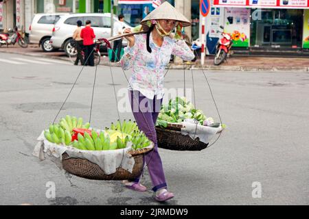 Street vendor selling fruit and vegetables from panniers, Hai Phong, Vietnam Stock Photo