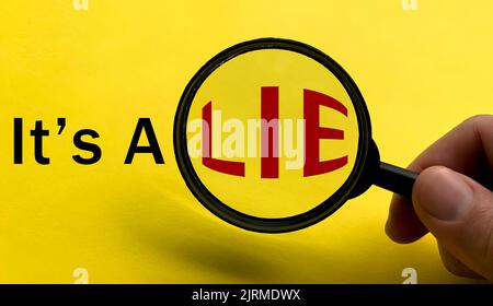It's a lie text on yellow cover with hand holding magnifying glass. Scamming and fraud concept. Stock Photo