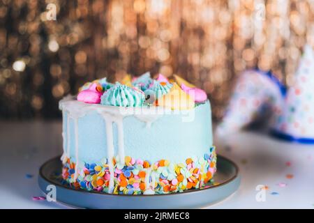 Colorful birthday cake with sprinkles and festive caps on the sparkling gold tinsel background. Festive birthday celebration, party. Selective focus, Stock Photo